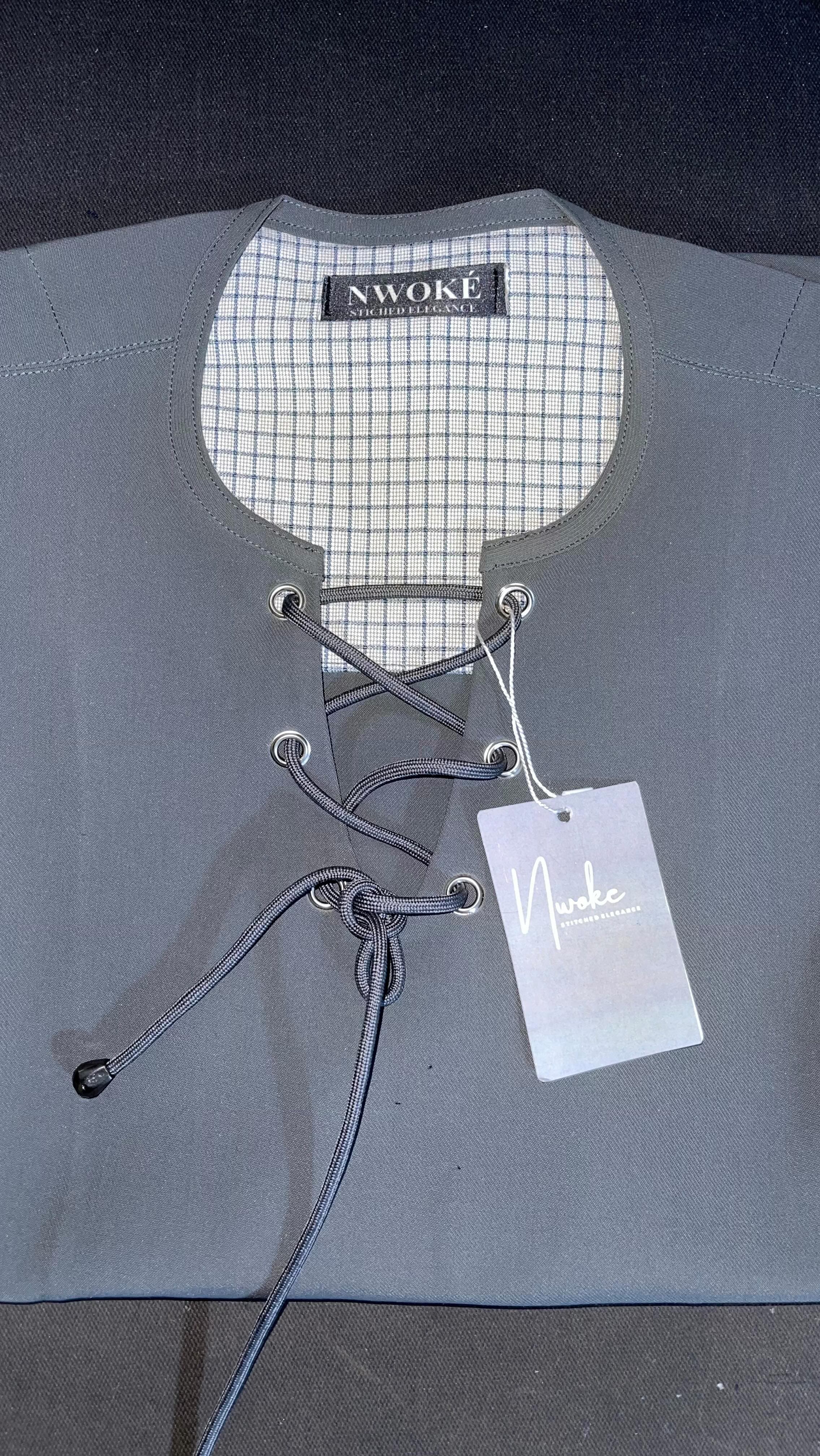 A grey top on a hanger with a cord-laced neckline and a NWOKÉ tag